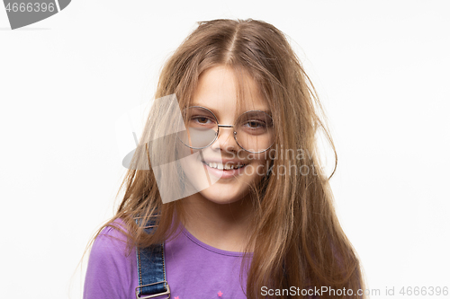 Image of Portrait of a cheerful tousled long-haired girl of eleven years in glasses