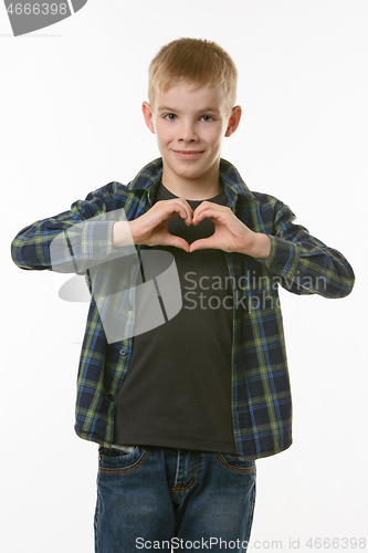 Image of A boy of ten years shows a heart with two hands on his chest