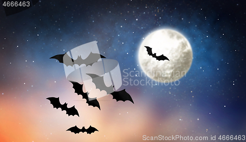 Image of black bats flying over moon in starry night sky