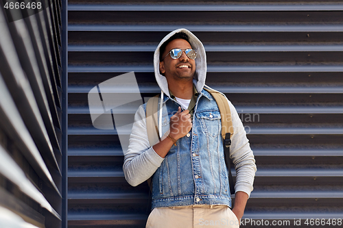 Image of smiling indian man with backpack on city street