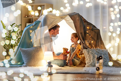 Image of happy family playing with toy in kids tent at home