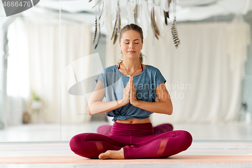 Image of woman meditating in lotus pose at yoga studio