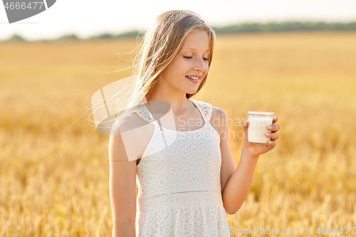 Image of happy girl with glass of milk on cereal field