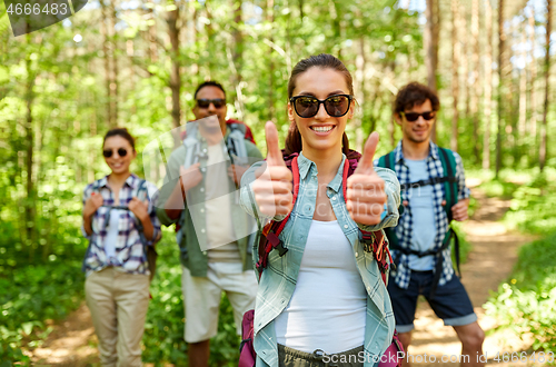 Image of friends with backpacks showing thumbs up in forest