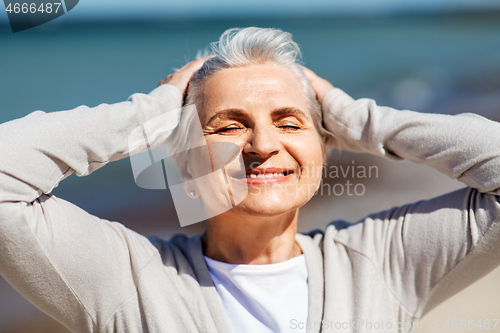 Image of portrait of senior woman enjoying sun on beach