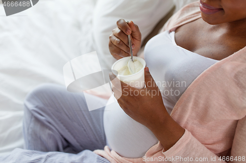 Image of pregnant woman eating yogurt for breakfast in bed