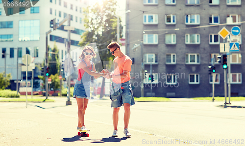 Image of teenage couple riding skateboards on city street