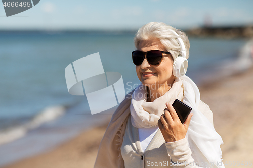 Image of senior woman using smartphone on beach