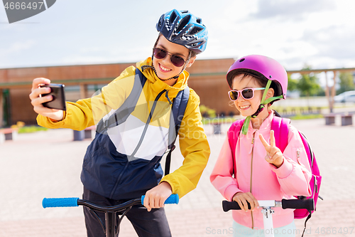 Image of happy school kids with scooters taking selfie