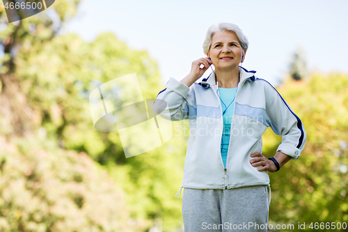 Image of senior woman with earphones at summer park