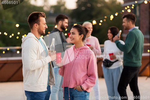 Image of friends with drinks in party cups at rooftop