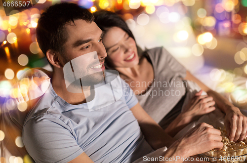 Image of couple with popcorn watching tv at night at home