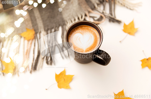 Image of coffee with latte art, autumn leaves and blanket