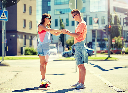 Image of teenage couple riding skateboards on city street