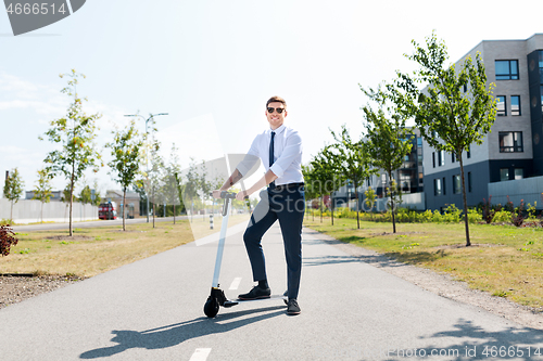 Image of young businessman riding electric scooter outdoors