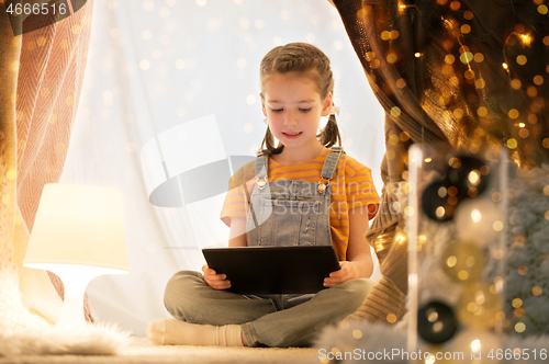 Image of little girl with tablet pc in kids tent at home