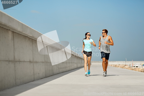 Image of couple in sports clothes running outdoors