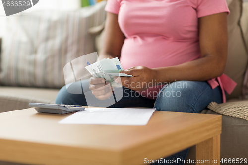 Image of pregnant woman counting money at home