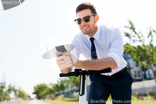 Image of businessman with smartphone and electric scooter