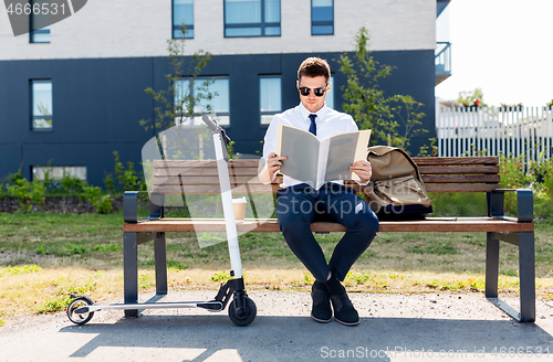 Image of businessman with file and scooter sitting on bench