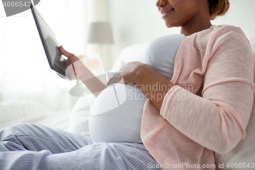 Image of close up of pregnant woman with tablet pc at home