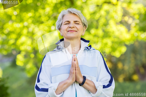 Image of happy senior woman doing yoga at summer park