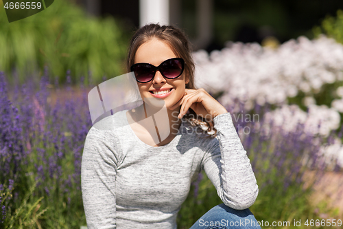 Image of happy young woman in sunglasses at summer garden