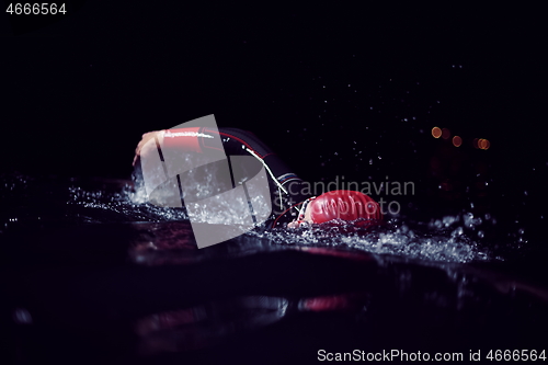 Image of triathlon athlete swimming in dark night wearing wetsuit