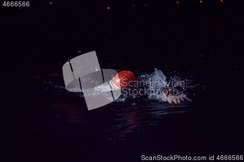 Image of triathlon athlete swimming in dark night wearing wetsuit