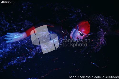 Image of real triathlon athlete swimming in dark night