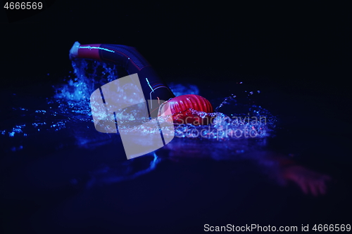 Image of real triathlon athlete swimming in dark night