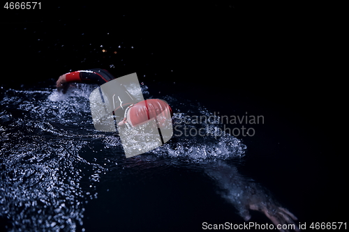 Image of triathlon athlete swimming in dark night wearing wetsuit