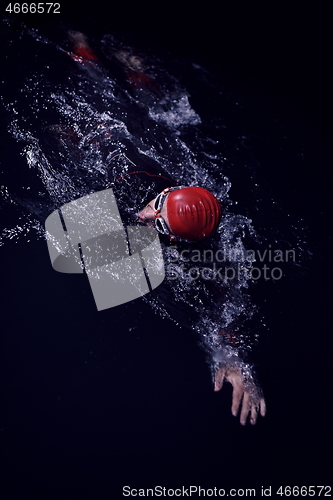 Image of triathlon athlete swimming in dark night wearing wetsuit