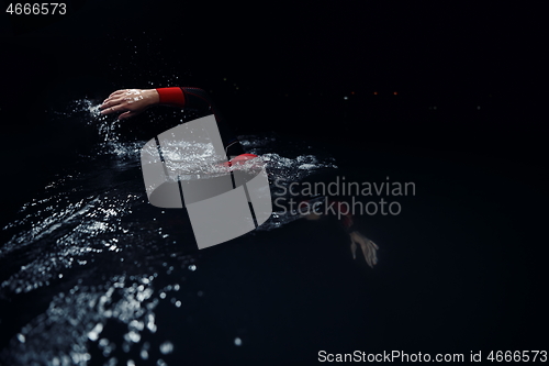 Image of triathlon athlete swimming in dark night wearing wetsuit