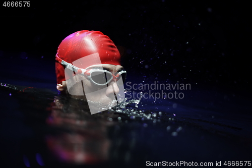 Image of authentic triathlete swimmer having a break during hard training on night