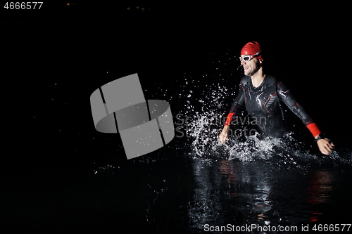 Image of triathlon athlete finishing swimming training at dark night