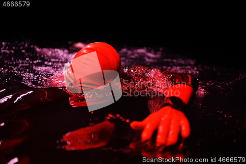 Image of real triathlon athlete swimming in dark night