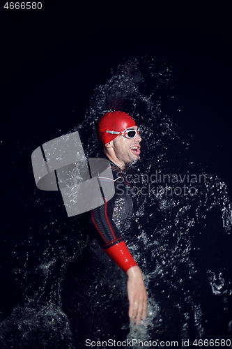 Image of triathlon athlete swimming in dark night wearing wetsuit