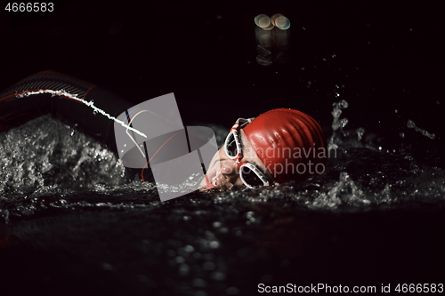 Image of triathlon athlete swimming in dark night wearing wetsuit