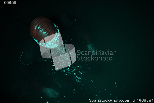 Image of authentic triathlete swimmer having a break during hard training on night neon gel light