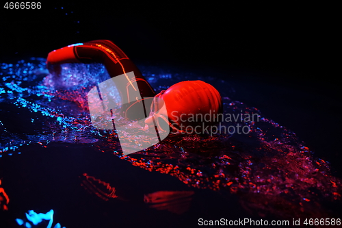 Image of real triathlon athlete swimming in dark night