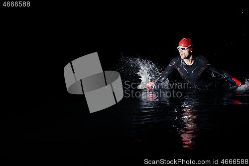 Image of triathlon athlete finishing swimming training at dark night