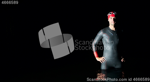 Image of authentic triathlete swimmer having a break during hard training on night