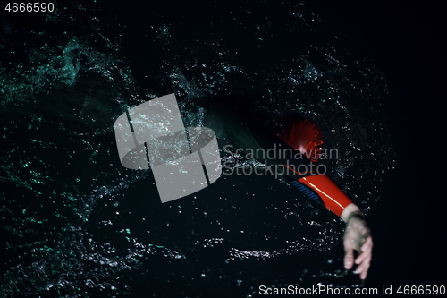 Image of real triathlon athlete swimming in dark night