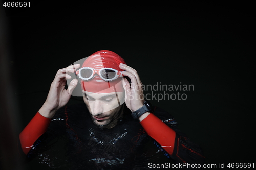 Image of authentic triathlete swimmer having a break during hard training on night