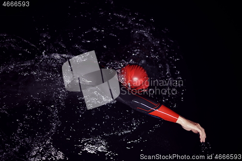 Image of triathlon athlete swimming in dark night wearing wetsuit