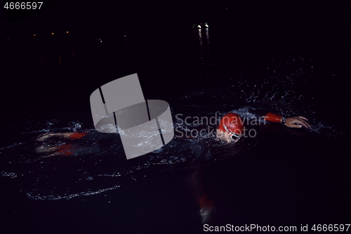 Image of triathlon athlete swimming in dark night wearing wetsuit