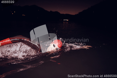 Image of triathlon athlete swimming in dark night wearing wetsuit