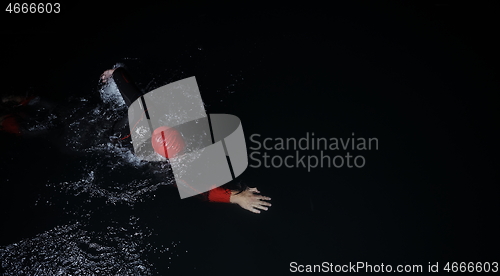 Image of triathlon athlete swimming in dark night wearing wetsuit