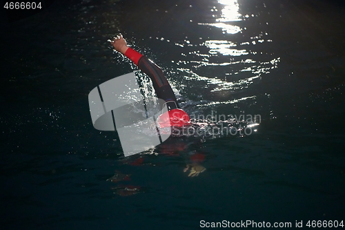 Image of triathlon athlete swimming in dark night wearing wetsuit